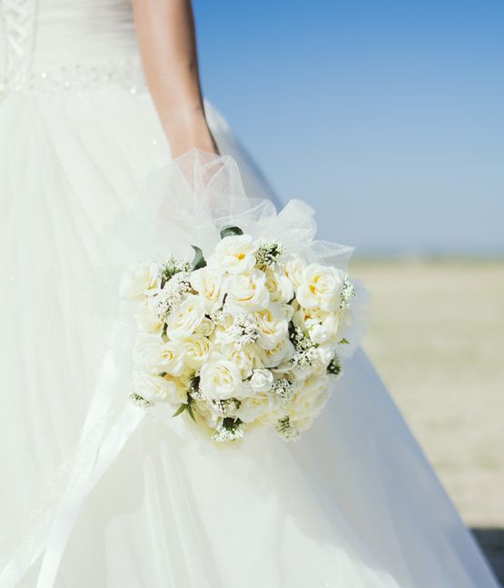 Frau trägt ihr Kleid nach der Brautkleidreinigung und hat Blumen in der Hand.